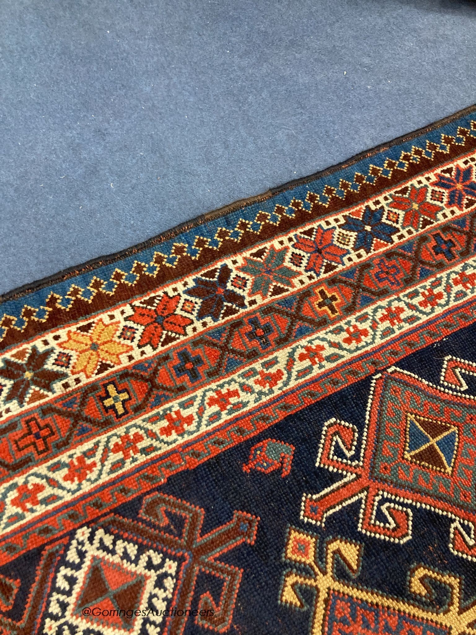 A Caucasian blue ground rug, woven with hooked lozenges, 288 x 152cm